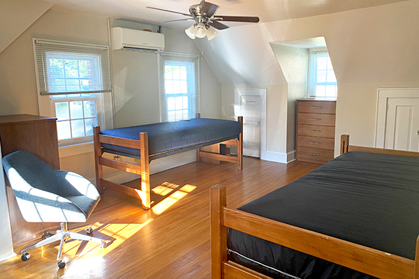 Recovery Housing bedroom with two lofted beds, dressers, chair, and wooden floors