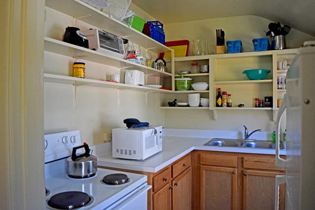 Kitchen includes stove, microwave, refrigerator, and built-in shelving
