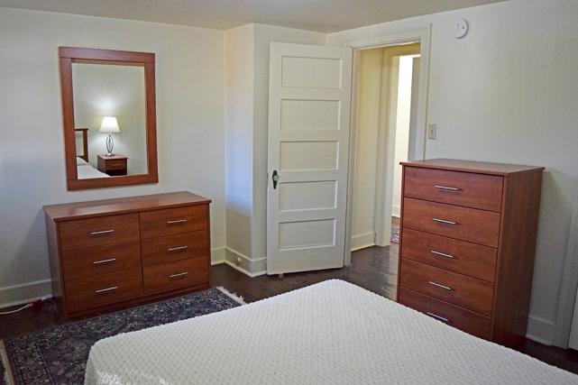Bedroom includes a full-size bed, dressers, and wall mirror